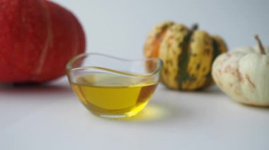 Temiz bir yüzey üzerinde zeytinyağı dolu bir kasenin yanına yerleştirilmiş çeşitli kabaklar.