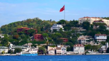 Büyüleyici evleri, canlı yeşillikleri ve Türk bayrağı olan güzel bir kıyı manzarası.