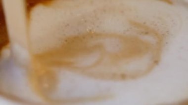 Bu, köpüklü girdaplarla kaplanmış kremalı kahvenin yakından görüntüsü.