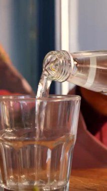 Bu, bir şişeden temiz bir bardağa dökülen suyu gösteren yakın plan bir görüntü.
