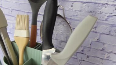 Tuğla zemin kaplamalı şık bir konteynırda düzenlenmiş mutfak gereçleri koleksiyonu.