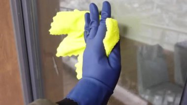 Mavi eldiven ile yeşil bez ile pencereyi temizleyin..