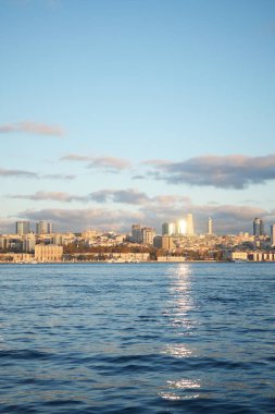 Gün batımında sakin sulara çarpıcı ve güzel bir şehir silueti yansıyor.