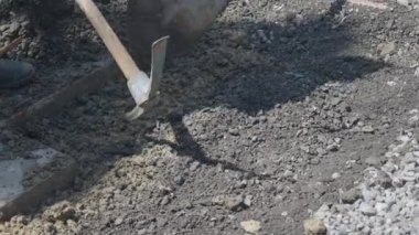 Güneş ışığının gölgeler bıraktığı bir inşaat alanında toprağı kazan bir işçi..