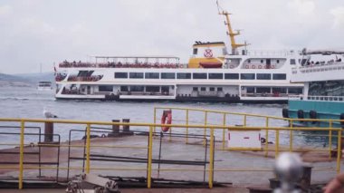 Kalabalık sahil terminaline büyük bir feribot geliyor, bir sürü hevesli yolcuyla birlikte.