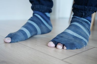 Ahşap zeminde aşınmış çizgili çorapların yakın çekimi.