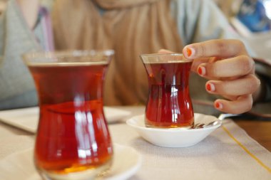 Geleneksel Türk çayını beyaz masada içen kadın 