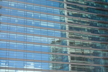 Çağdaş bir ofis binasının modern ve gösterişli dış görünüşü büyük cam pencereler sergiliyor.