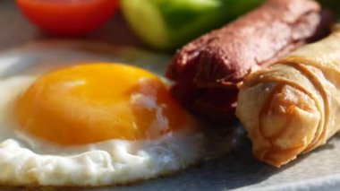 Canlı bir kahvaltı tabağı, kızarmış yumurta, lezzetli sosis ve çıtır börek.