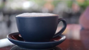 Bu, çay tabağına konmuş köpüklü bir içecekle dolu güzel yapılmış bir kahve fincanı.