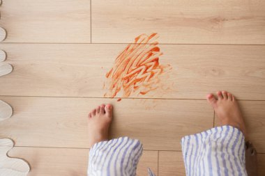 Neşeli bir sahne, ahşap bir zeminde küçük ayaklarla canlı renk çizgileri yakalar.