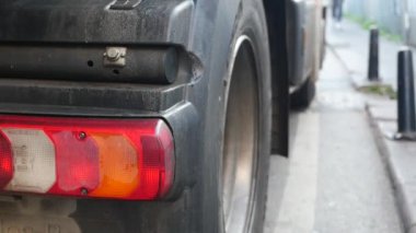 Yoğun bir caddede arka lambası ile birlikte bir kamyonun arka lastiğinin detaylı ve yakın görüntüsü