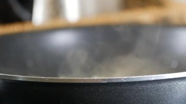 Kara tavadan buhar yükseliyor, zarif bir şekilde yemek pişirmede büyüleyici bir an sergiliyor.