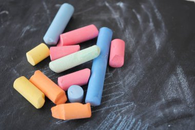 Karatahtaya serpiştirilmiş renkli ve canlı tebeşir parçaları koleksiyonu.