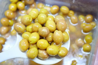 Bir kabın içinde güzelce sergilenmiş canlı yeşil zeytinlerden oluşan renkli bir karışım.