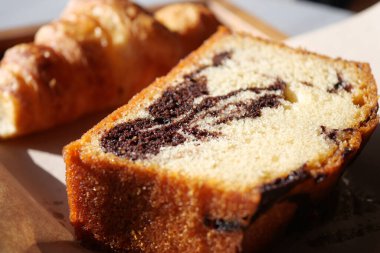 Zengin ve nemli çikolatalı mermer pasta. Arka planda tereyağlı kruvasan var.