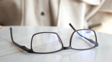 Zarif ve zarif gözlükler güzel bir mermer masa yüzeyinde huzur içinde dinleniyor.