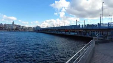 Hareketli bir gökyüzünün altında ufku boyayan sakin suların üzerine uzanan pitoresk bir iskele.