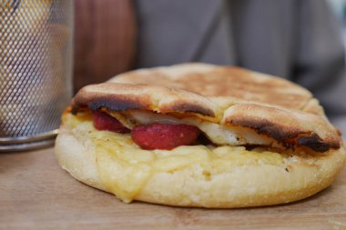 Tatmin edici bir kahvaltı sandviçi. Yumurta, peynir ve baharatlı sosis karışımı.