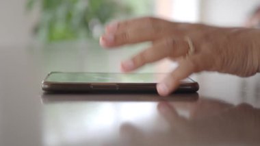 Adam el masadan akıllı telefon alıyor.