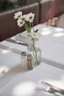 Bu büyüleyici ve zarif masa dekorunda bir vazoda sanatsal olarak dizilmiş güzel çiçekler var.