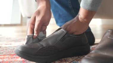 Bir insan temiz ve düzenli görünmesi için siyah ayakkabıları bezle parlatır.