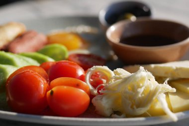 Taze domatesli renkli bir Akdeniz tabağı, aromalı peynir ve lezzetli zeytinler.