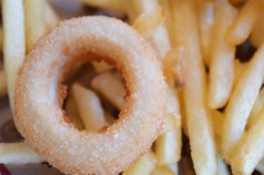 Çıtır bir soğan halkası stratejik olarak lezzetli kızarmış patateslerin arasına yerleştirilir.