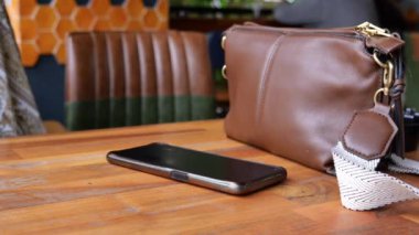 Adam el masadan akıllı telefon alıyor.