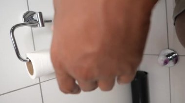 Bir el, tuvalet kağıdını temiz ve düzenli bir banyodaki bir tutacağa yerleştirme işlemindedir.