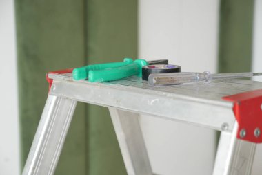 Sağlam bir merdiven üzerinde ev geliştirme projelerine hazır çeşitli temel araçlar.