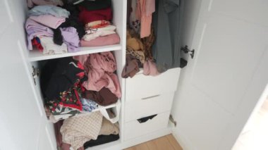Çeşitli giyim eşyaları ve aksesuarlarla dolu dağınık bir dolap.