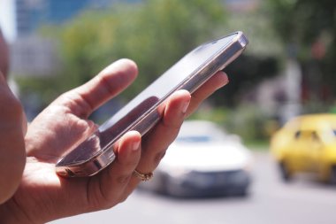 Meşgul şehir trafiği ve araçlarında gezinirken akıllı telefonu sıkıca kavrayan bir el