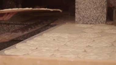 Zanaatkar fırıncılar taze, yumuşak hamur şekillerini ustalıkla pişirmek için lezzetli düz ekmeklere dönüştürüyorlar.