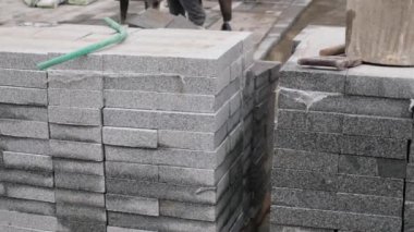 Gri granit kaldırımlar düzgünce yerleştirilmeyi bekleyen bir inşaat sahasına istiflenmiş..