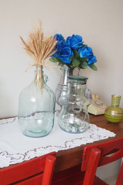 Altın buğdaylı ve mavi çiçekli büyüleyici vazolar kırsal bir masaya güzelce yerleştirilmiş.