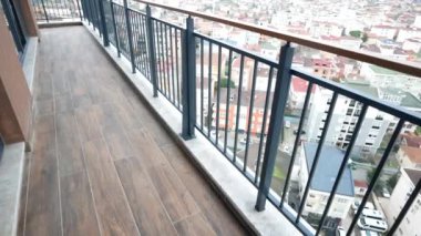 Bu balkon tasarımı zarif ahşap döşemeler ve çarpıcı bir şehir manzarası içeriyor.
