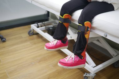 Ortopedik diş telli Childs Legs ve Klinik Yatağında Parlak Pembe Ayakkabılar.