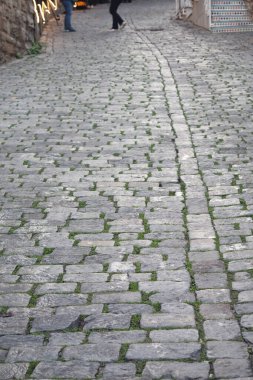 Bu görüntü, karmaşık desenli, dokulu bir kaldırım taşı sokağının yakın çekimini gösteriyor.