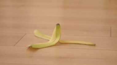 Çıplak ayak muz kabuğunda kayıyor Tahta zemin yüzeyinde kabuk,