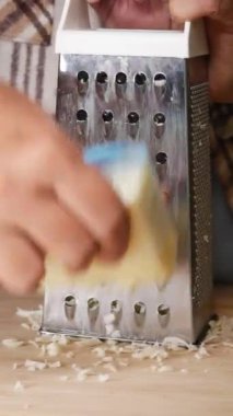 Taze rendelenmiş peynir ahşap bir yüzeyde duran metal rendesinin yanına güzelce istiflenmiş.