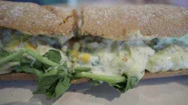 Kremalı sos ve taze yeşilliklerle dolu lezzetli bir sandviç.