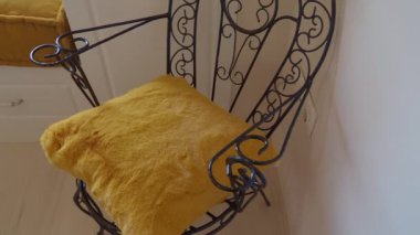 Bu şık demir sandalye, maksimum konfor ve rahatlama için yumuşak sarı bir yastıkla tasarlanmıştır.