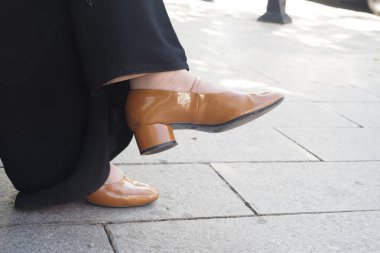 Zarif kahverengi patentli Mary Jane ayakkabılarının entelektüellik için harika yay aksanları var.