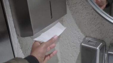 Temiz umumi tuvaletteki beyaz fayanslı bir kutudan kağıt havlu alıyorum..