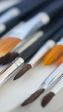 Bir dizi canlı boya fırçası dikkatle boş bir tuval üzerinde dinleniyor, sanat yaratmaya hazır.