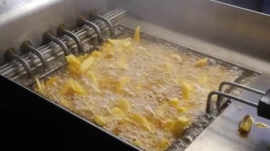 Kızartma makinesinde kızaran kızarmış patateslerle birlikte kaynayan kızgın yağ var.