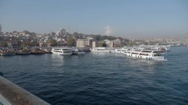 İstanbul rıhtımının güzel manzarasında kayıklar ve şehrin ufuk çizgisi yer alıyor