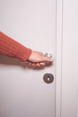Bir insan eli kapı kolunu sıkıca kavrıyor, dengeli ve önemli bir kapıyı açmaya hazır.