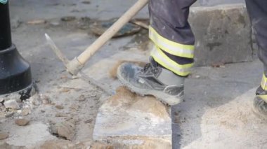 Bir inşaat işçisi şehirde sağlam bir kazma aletiyle ustalıkla zemin hazırlıyor.